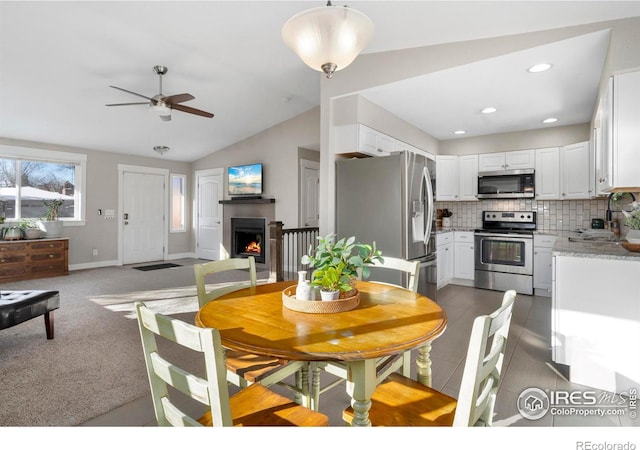 dining area featuring lofted ceiling, carpet floors, and ceiling fan