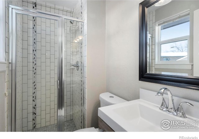 bathroom featuring vanity, toilet, and a shower with door