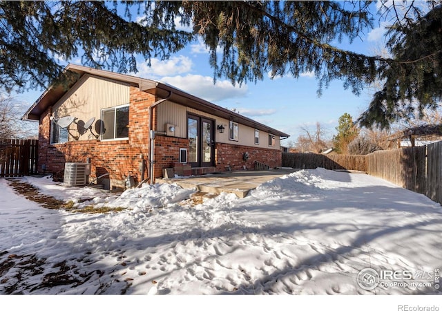 snow covered property featuring central AC and french doors