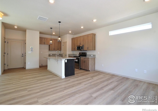 kitchen featuring appliances with stainless steel finishes, a breakfast bar, an island with sink, hanging light fixtures, and light stone counters