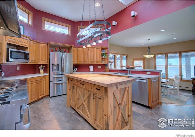 kitchen featuring butcher block countertops, hanging light fixtures, a center island, stainless steel appliances, and a water view