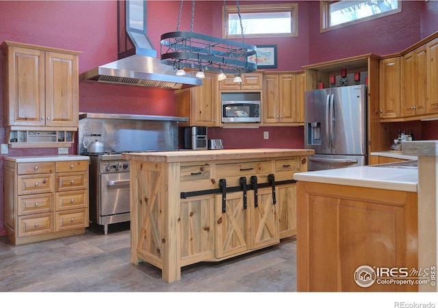 kitchen featuring a high ceiling, island exhaust hood, appliances with stainless steel finishes, and decorative light fixtures