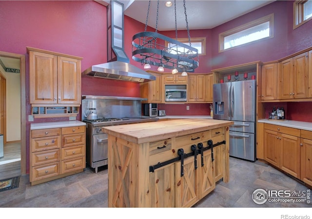 kitchen with wooden counters, appliances with stainless steel finishes, hanging light fixtures, a high ceiling, and island range hood