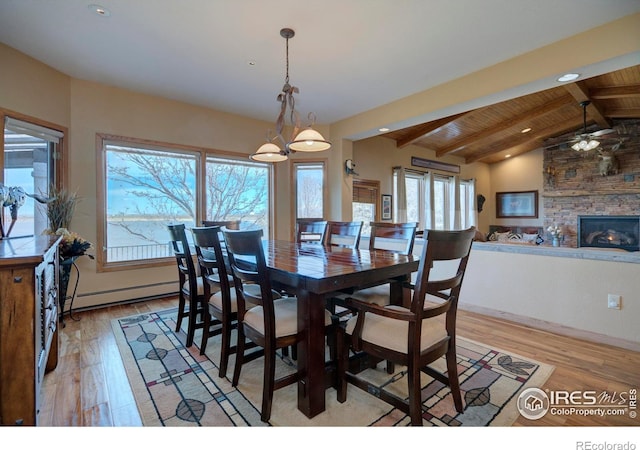 dining space featuring vaulted ceiling with beams, wooden ceiling, baseboard heating, light wood-type flooring, and a fireplace