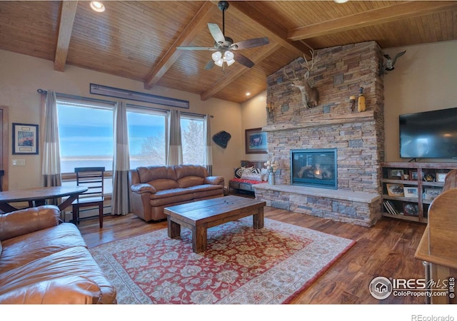 living room featuring hardwood / wood-style flooring, beam ceiling, high vaulted ceiling, a stone fireplace, and wooden ceiling