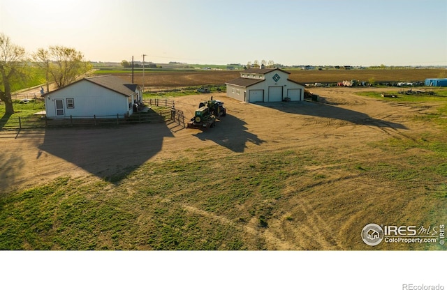 view of yard with a rural view, a garage, and an outbuilding