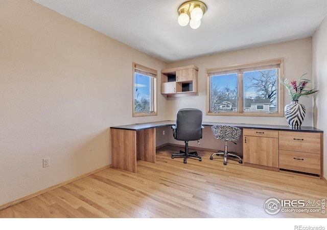 home office with light wood-style floors, baseboards, and built in study area