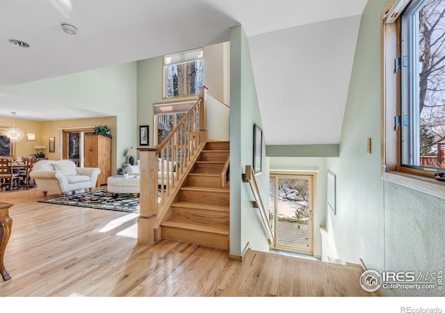 stairs featuring a chandelier, wood finished floors, and a towering ceiling