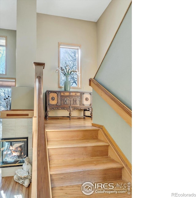 staircase with a tiled fireplace and a healthy amount of sunlight