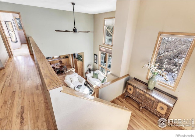 interior space featuring light wood-type flooring, a high ceiling, and a ceiling fan