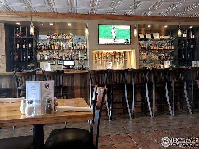 bar featuring an ornate ceiling, decorative light fixtures, and a bar