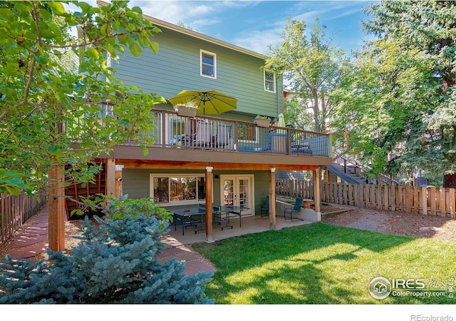 back of property with french doors, a patio, a wooden deck, and a lawn