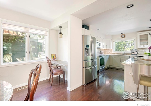 kitchen featuring appliances with stainless steel finishes, pendant lighting, tasteful backsplash, white cabinetry, and sink