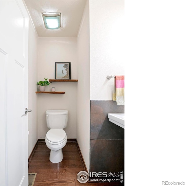 bathroom with hardwood / wood-style flooring, a textured ceiling, and toilet