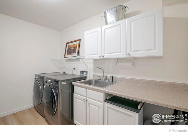 laundry room featuring cabinets, sink, washing machine and clothes dryer, and light wood-type flooring