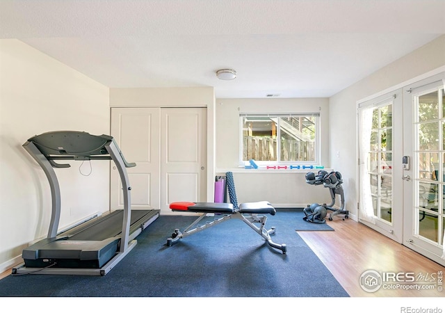 workout room with hardwood / wood-style flooring, french doors, and a textured ceiling