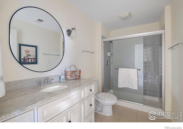 bathroom featuring vanity, a shower with door, tile patterned floors, and toilet