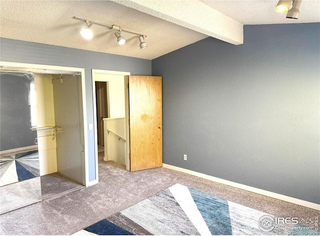 unfurnished bedroom with beam ceiling, carpet, a textured ceiling, and a closet