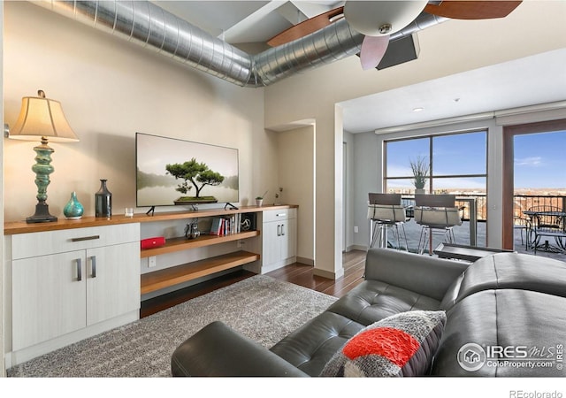 living room with plenty of natural light, ceiling fan, baseboards, and dark wood-style flooring