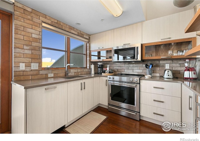 kitchen with decorative backsplash, appliances with stainless steel finishes, stainless steel counters, open shelves, and a sink