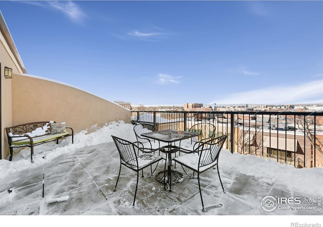 snow covered patio with a balcony and outdoor dining area