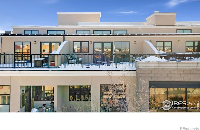 snow covered house featuring stucco siding