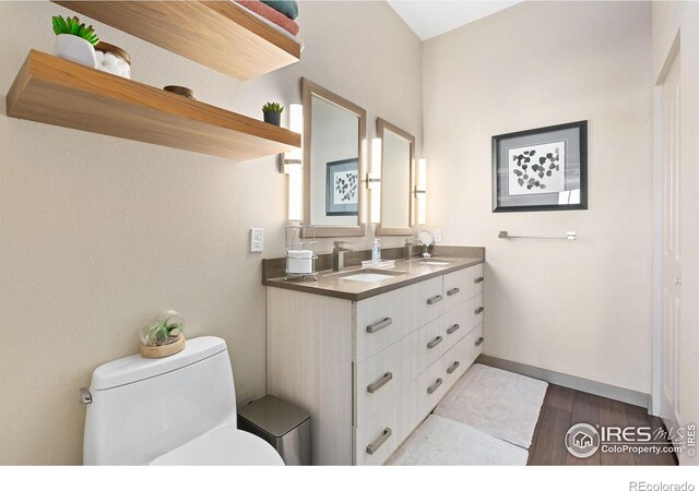 bathroom with double vanity, toilet, a sink, and wood finished floors