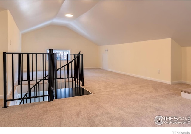 bonus room with light carpet and vaulted ceiling