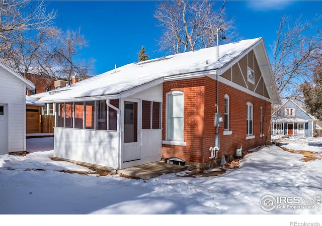 view of snowy exterior with a sunroom