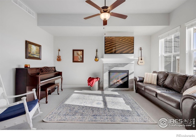 living room with ceiling fan, carpet floors, and a tile fireplace