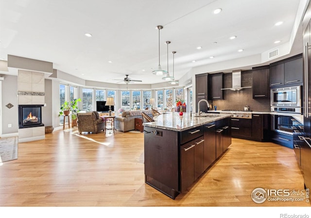 kitchen with stainless steel appliances, tasteful backsplash, a kitchen island with sink, and dark brown cabinetry