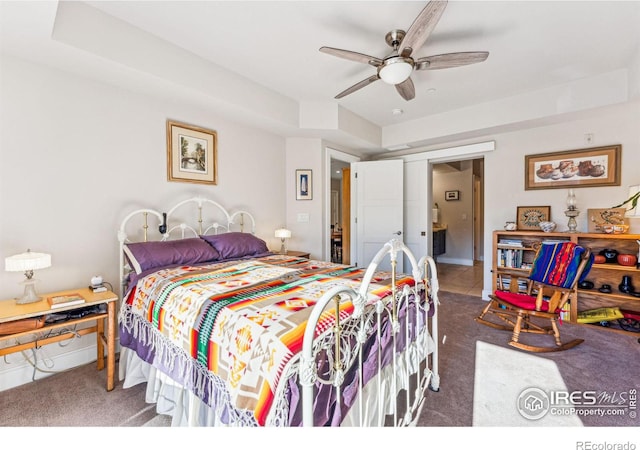 carpeted bedroom featuring a raised ceiling and ceiling fan