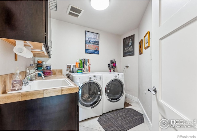 clothes washing area with washing machine and dryer, sink, and light tile patterned floors