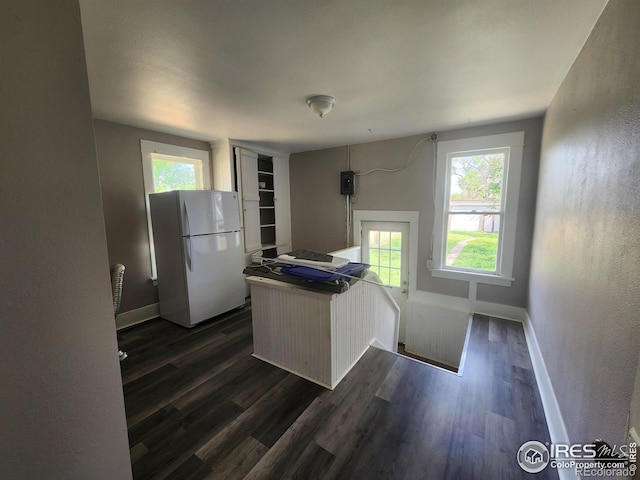 kitchen with white cabinetry, dark wood-type flooring, kitchen peninsula, and white fridge