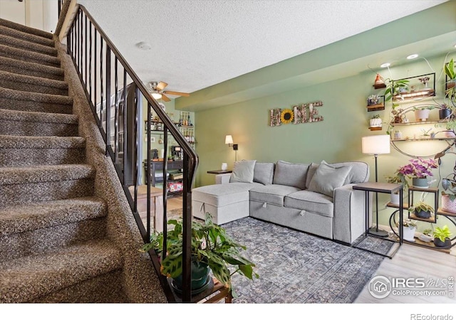 living room featuring hardwood / wood-style floors, a textured ceiling, and ceiling fan