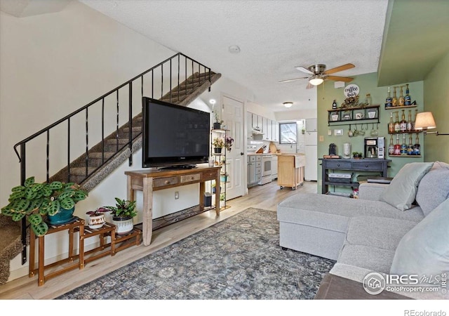 living room featuring hardwood / wood-style flooring, ceiling fan, sink, and a textured ceiling