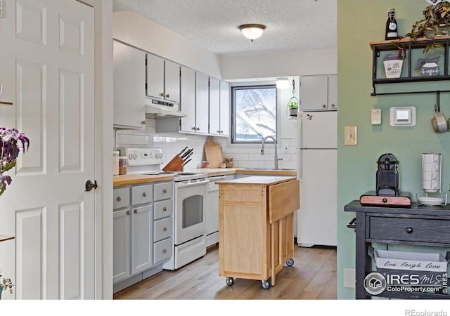 kitchen featuring butcher block countertops, sink, white cabinets, a center island, and white appliances