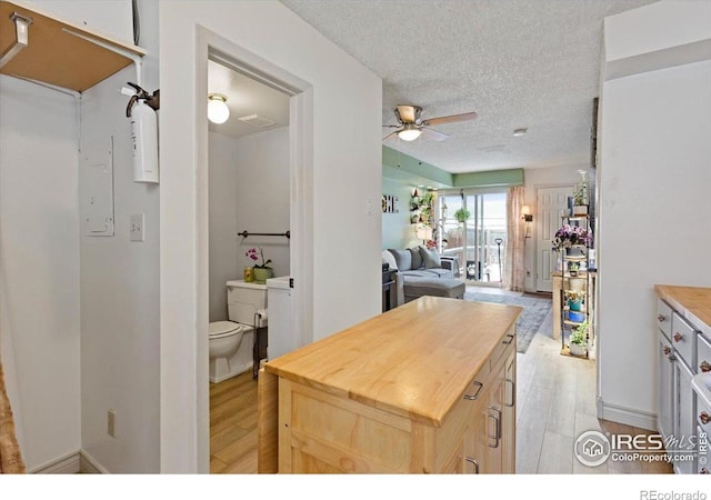 kitchen featuring wooden counters, ceiling fan, light hardwood / wood-style floors, light brown cabinets, and a textured ceiling