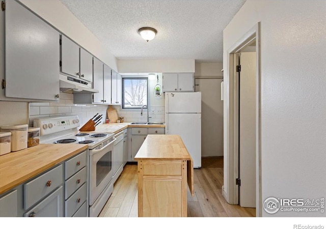 kitchen with butcher block counters, sink, gray cabinetry, a kitchen island, and white appliances