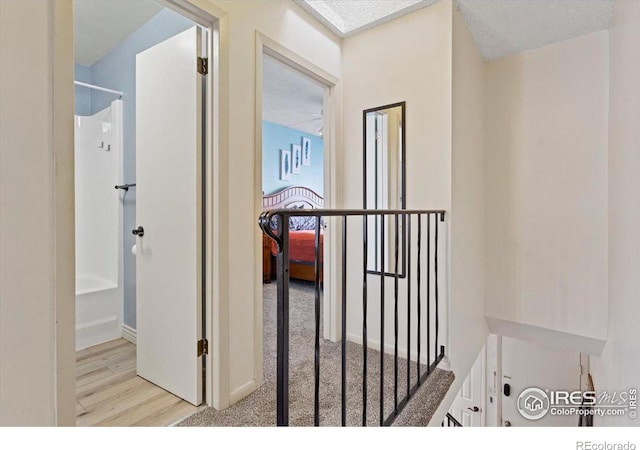 hallway with a textured ceiling and light wood-type flooring