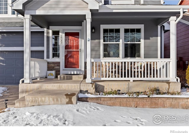 snow covered property entrance with a garage