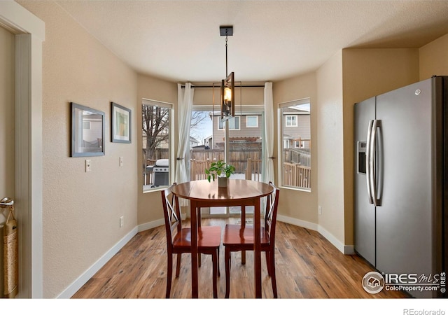 dining room featuring light wood-type flooring, baseboards, and an inviting chandelier