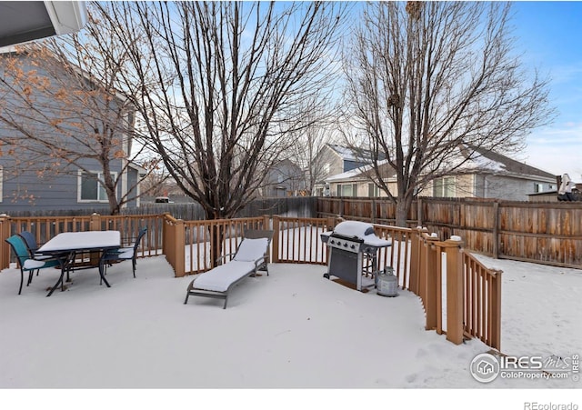 snow covered deck featuring a fenced backyard, area for grilling, and outdoor dining space