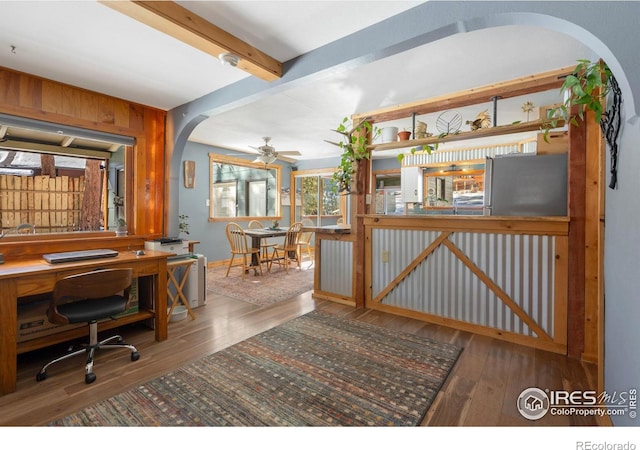 office space with wood-type flooring, arched walkways, beam ceiling, and ceiling fan