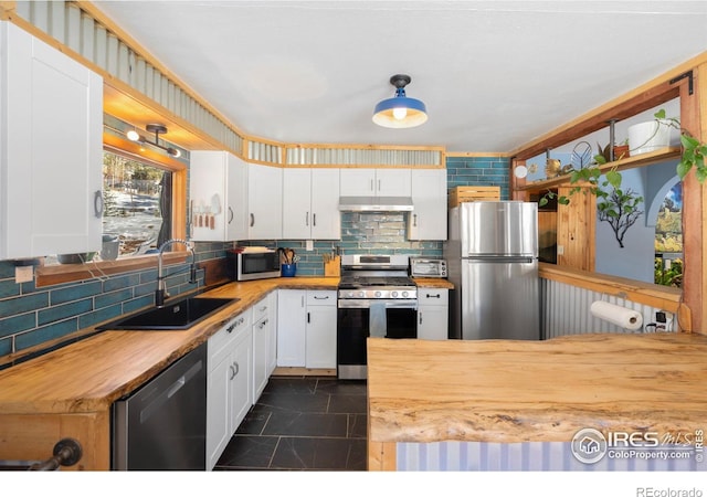 kitchen featuring stainless steel appliances, butcher block countertops, sink, and white cabinets