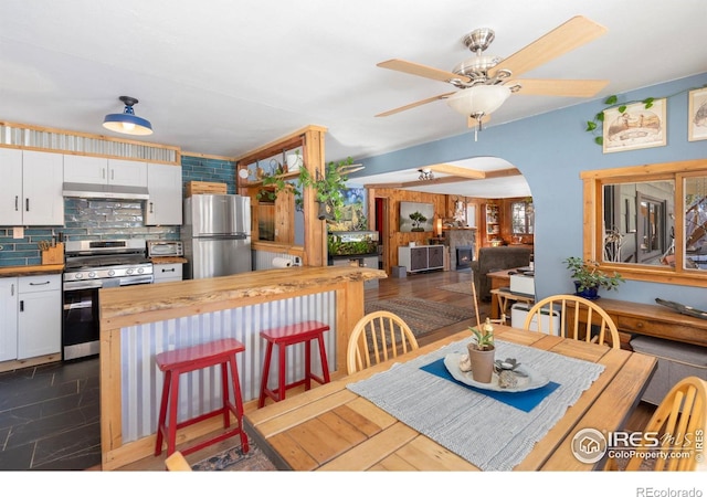 dining room with a toaster, a ceiling fan, and arched walkways