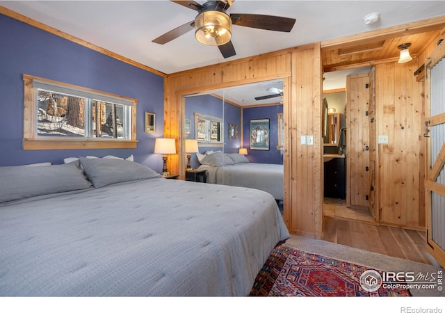 bedroom featuring wooden walls, wood finished floors, a closet, and ceiling fan