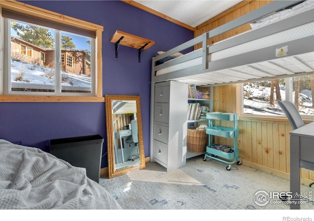 bedroom featuring carpet floors, multiple windows, and wood walls