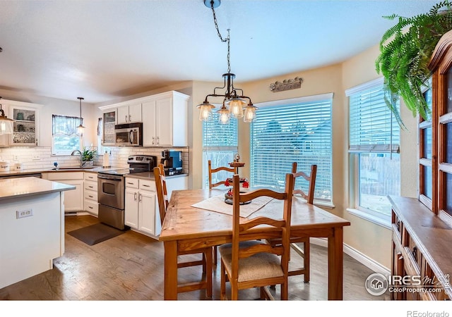 kitchen with stainless steel appliances, white cabinetry, tasteful backsplash, and decorative light fixtures