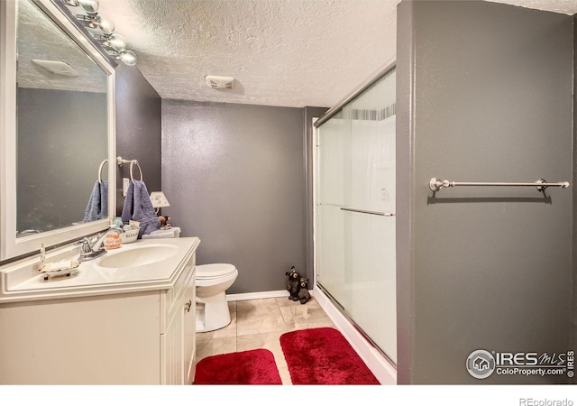 bathroom featuring a shower with shower door, tile patterned flooring, vanity, toilet, and a textured ceiling